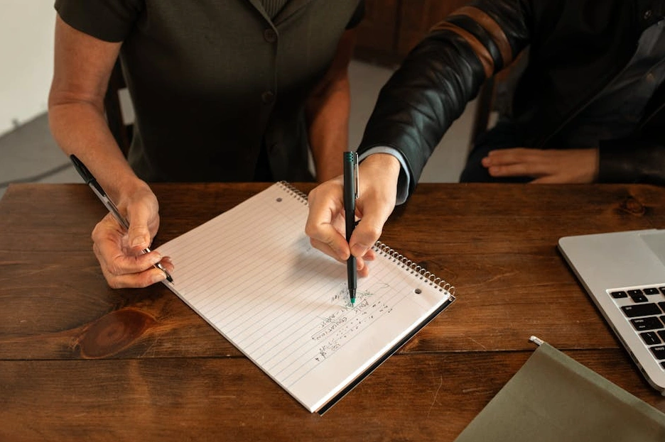 Osoba zapisująca notatki w notesie podczas kreatywnego spotkania